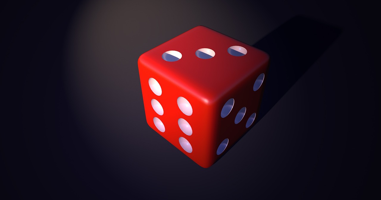 A red six-sided die with white dots representing numbers is shown against a dark background, casting a shadow to the right.