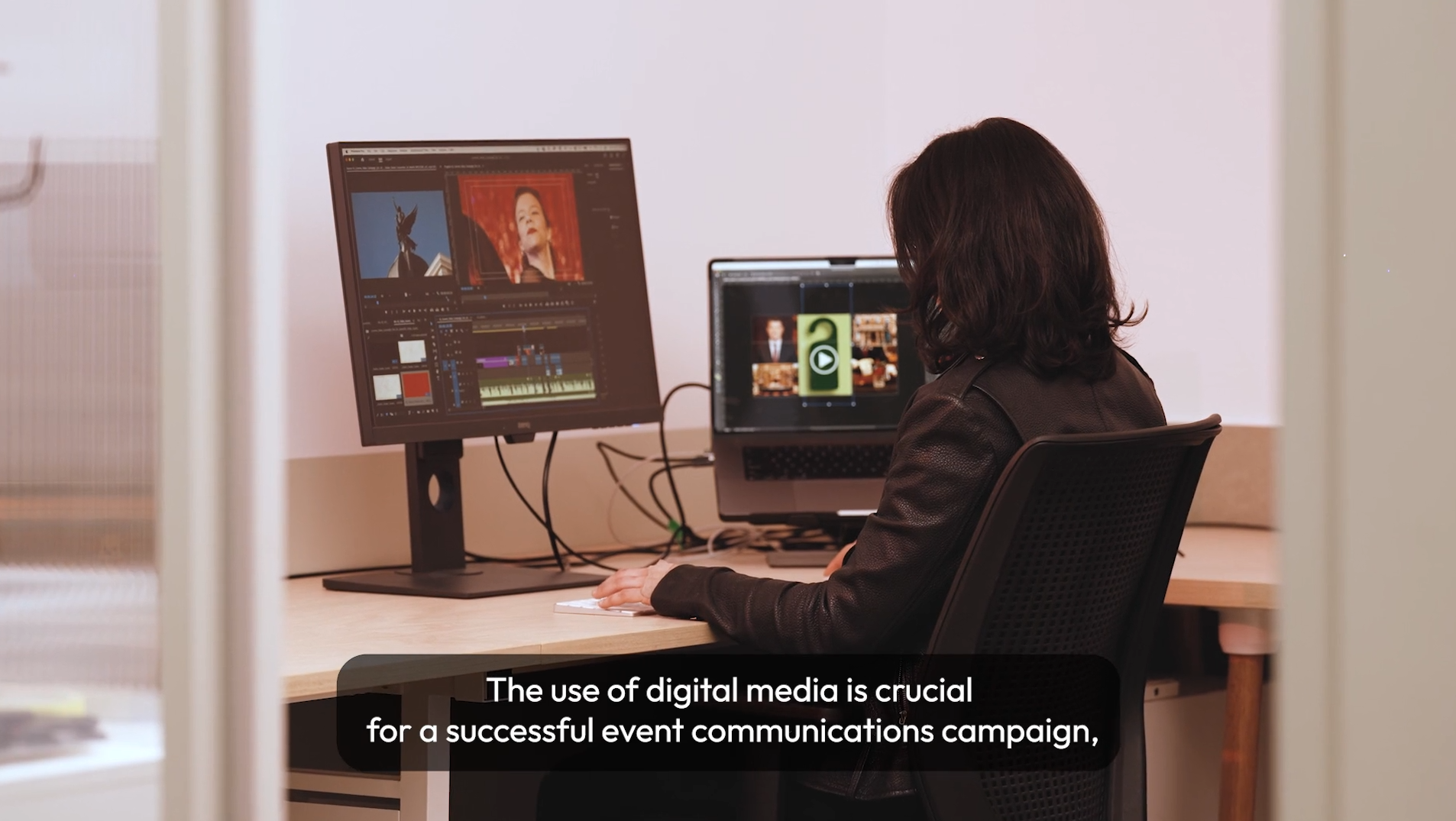 A person with dark hair and a leather jacket is sitting at a desk working on video editing software on a computer with two screens. There is a text overlay saying, The use of digital media is crucial for a successful event communications campaign.